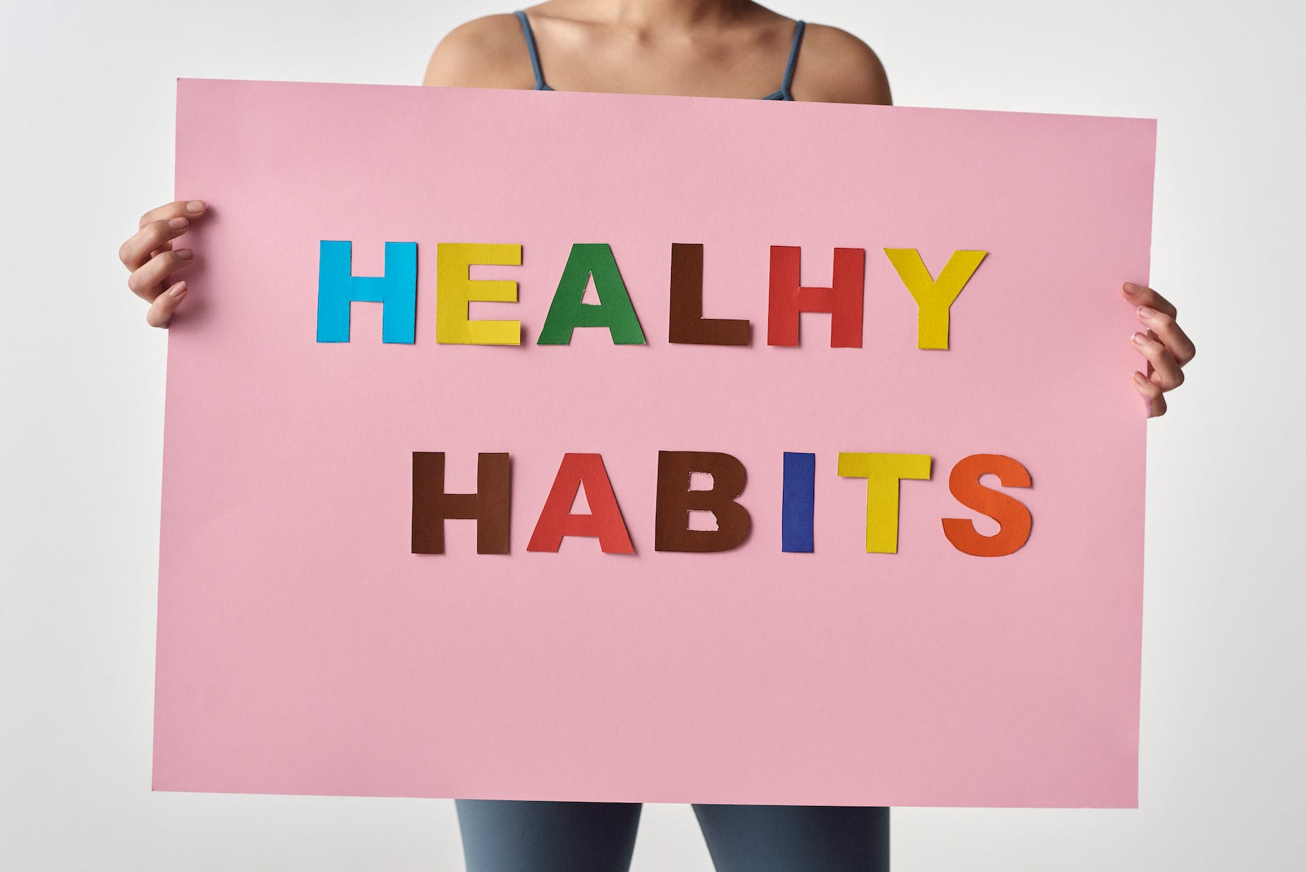 person holding a pink poster with message saying healthy habits
